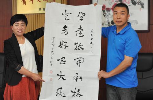 省经济电视台高级记者、省诗词协会会员为省民政厅副厅长陈慈英（左）送上墨宝