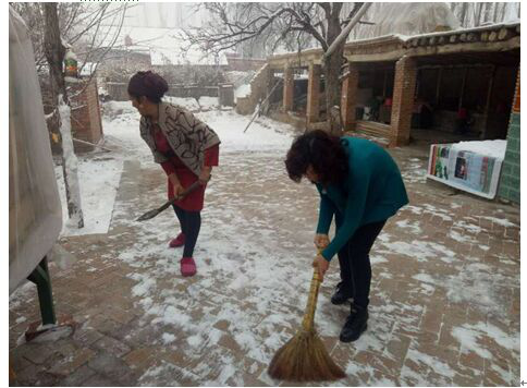 伊犁州福彩中心干部（右）与“亲戚”一同清扫院子积雪