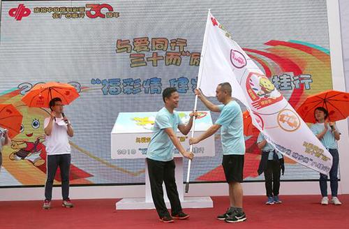 广西福彩中心杨志刚副主任向南宁市福彩中心徐辉龙主任授旗