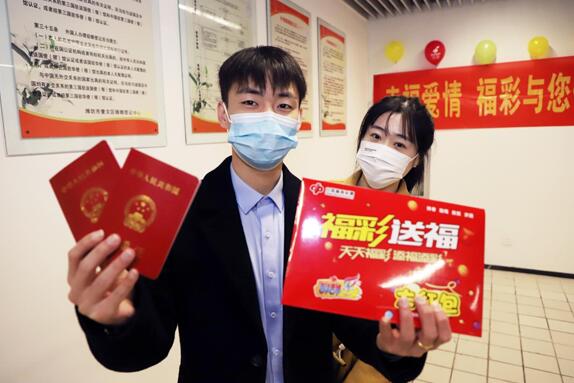 新人们拿着“小红本”和“福彩礼包”